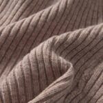 Close-up of a light camel 100% merino wool cuffed beanie hat, showcasing its soft knit texture.