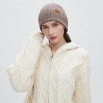 Close-up of a light camel 100% merino wool cuffed beanie hat, showcasing its soft knit texture.
