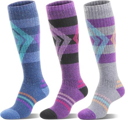 Three pairs of striped Welwoos Merino wool thermal ski socks in blue, purple, and grey, folded neatly.